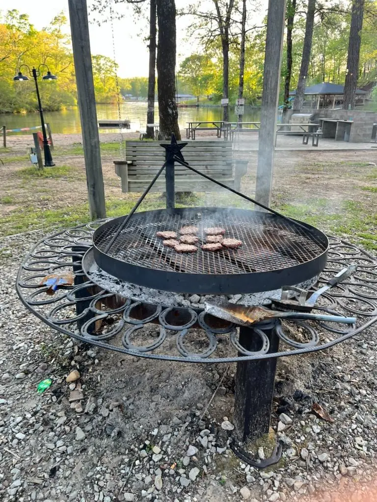 Burgers on the round grill over the fire pit, with the cove behind