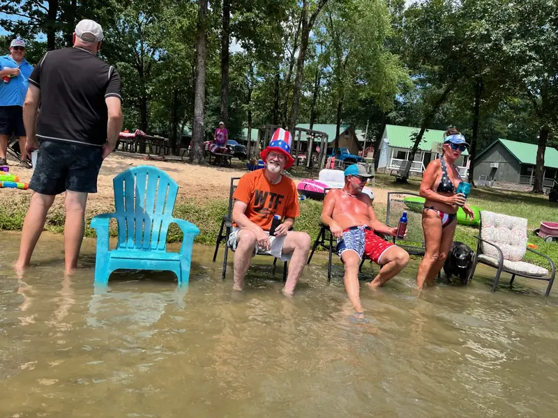 Guests sitting in the shallow water with the cabins behind them