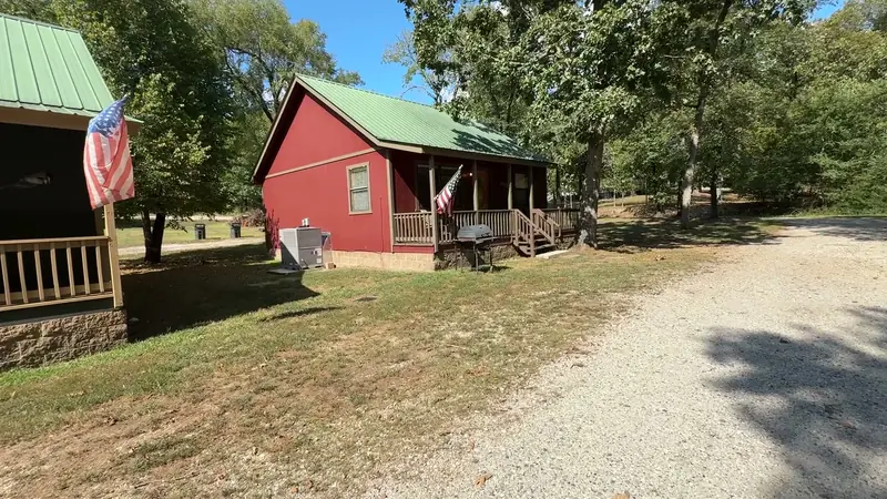 A red cabin with a green metal roof beside the lane